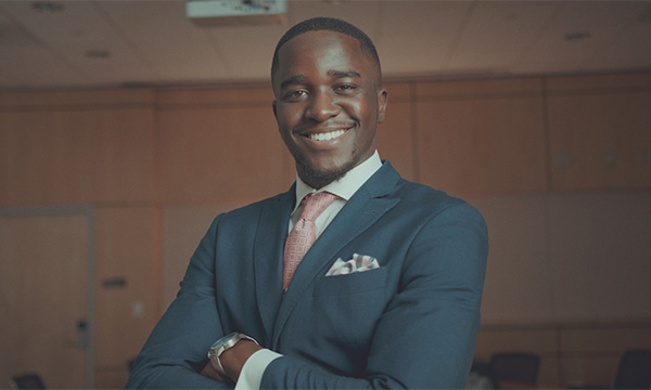 Man in a suit standing cross-armed smiling at the camera