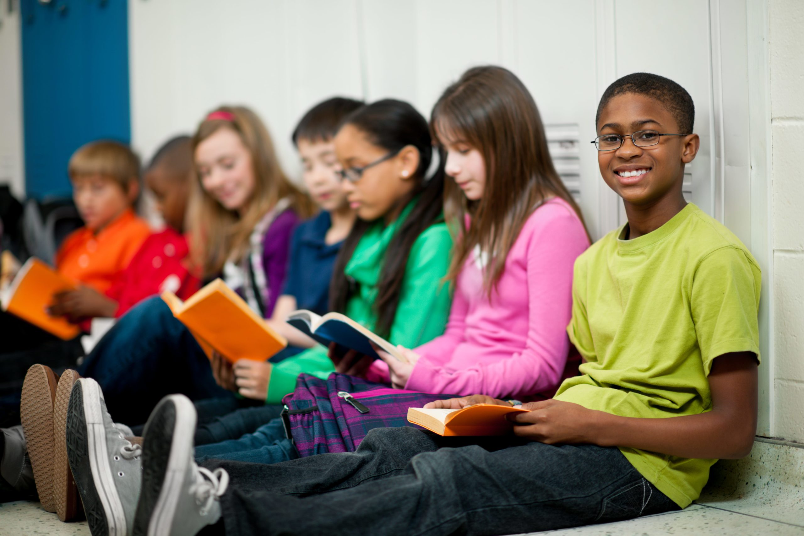 students sitting against lockers